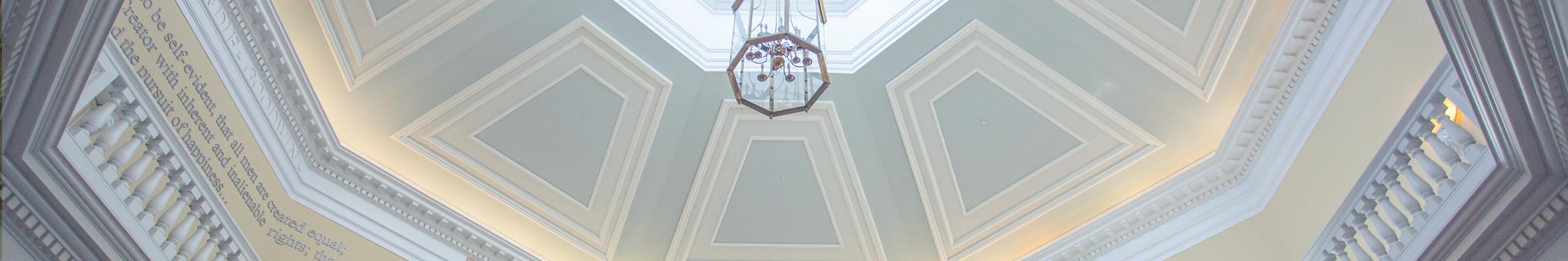 A banner portrait of a rounded ceiling with a chandelier hanging in the center.